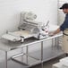 A man using an Estella countertop dough sheeter to cut dough.