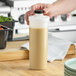 A person pouring a Server 1 liter white bottle of brown liquid into a container.