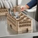 A person putting utensils in a beige Vollrath Traex flatware rack.