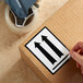 A hand applying a Lavex black up arrow label to a cardboard box.