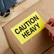 a hand holding a yellow sign on a cardboard box
