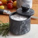 A Fox Run black marble salt cellar with salt inside on a kitchen counter.