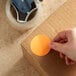 A hand holding a Lavex round orange inventory label sticker on a cardboard box.