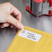 A person's hand pointing at a Globe white label on a yellow envelope.