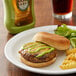 A plate of food with a burger and fries with a bottle of Kikkoman wasabi sauce on the side.