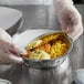 A person in gloves holding a Choice foil-laminated board lid over a tray of food.