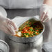 A person in gloves putting food in a Choice foil container.