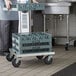 A person holding a Regency aluminum glass rack dolly with a glass rack on it.