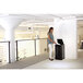 A woman standing in front of a Fellowes AutoMax 350C shredder throwing paper in a black trash can.