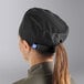 A woman wearing a black Uncommon Chef skull cap with a ponytail.