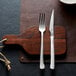 An Amefa stainless steel meat fork and knife on a cutting board.