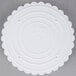 A white plastic Wilton cake separator plate with scalloped edges.