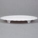 A white plastic Wilton cake separator plate with a scalloped edge.