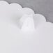 A white plastic Wilton cake separator plate with scalloped edges.