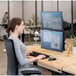 A woman sitting at a desk using two Fellowes black dual monitor arms.