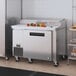 A stainless steel Hoshizaki commercial refrigerator with vegetables on top.