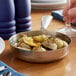 A Vollrath mini stainless steel fry pan of food on a table.