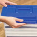 A person holding a blue Bankers Box plastic file box with a handle.