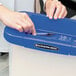 A woman putting a pen in a blue Bankers Box portable file container.