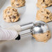 A hand using a Vollrath Jacob's Pride beige disher to scoop cookie dough.