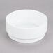 An Arcoroc white porcelain stackable bowl on a gray surface.