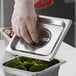 a hand holding a lid of broccoli