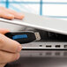 A hand holding a Verbatim Store 'n' Go V3 USB flash drive in front of a laptop.