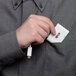 A hand holding a small white Tripp Lite USB-C to VGA adapter in a pocket.