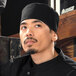 A man wearing a Uncommon Chef black chef's skull cap.