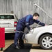 A man in blue overalls looks at a car with a Guardian black anti-fatigue floor mat under the car.