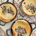 A pan of pancakes topped with blueberries and powdered sugar with a fork on a table.