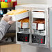 A person putting a container of cheese sauce into a Carnival King dual peristaltic dispenser.