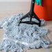 A Carlisle mop handle with a plastic head on the floor with a mop.