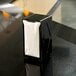 A black San Jamar Tallfold Tabletop Napkin Dispenser on a counter.