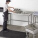 A man standing at a Regency stainless steel sorting table.