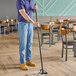 A man using a Carlisle Sparta vinyl-coated metal mop handle with a plastic head to mop the floor of a farm-to-table restaurant.