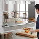 A woman holding a container of food on a Regency stainless steel pass-through shelf.