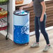 A woman putting a plastic bottle in a Galaxy Cold Drink Barrel Refrigerator.