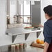 A woman in a kitchen with a Regency stainless steel shelf on the wall above the counter.
