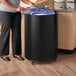 A woman standing next to a black Galaxy merchandiser freezer holding a can of food.