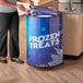 A woman in black pants standing in front of a Galaxy glass door merchandiser freezer filled with frozen treats.