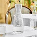 A Front of the House clear plastic carafe filled with clear liquid on a table.