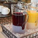 A table with a Front of the House Drinkwise pitcher of juice in ice.