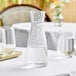 A Front of the House Drinkwise clear plastic carafe on a table with a glass of clear liquid.