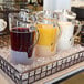 A Front of the House plastic pitcher with orange liquid on a table.