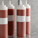 A group of sauce bottles with white Puracycle bottlewrap labels.