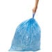 A hand holding a blue simplehuman recycling liner.