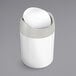 A white simplehuman countertop swing top trash can.