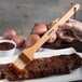 A person painting ribs on a plate with a Carlisle boar bristle brush.