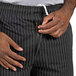 A man zipping up Uncommon Chef black and white pinstripe chef pants.